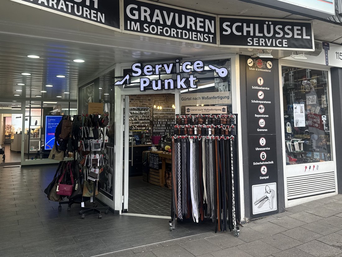 Die Ladenfront an der Dellbrücker Hauptstraße 115 mit den Schildern für Schuhreparaturen, Gravuren im Sofortdienst und Schlüsselservice.