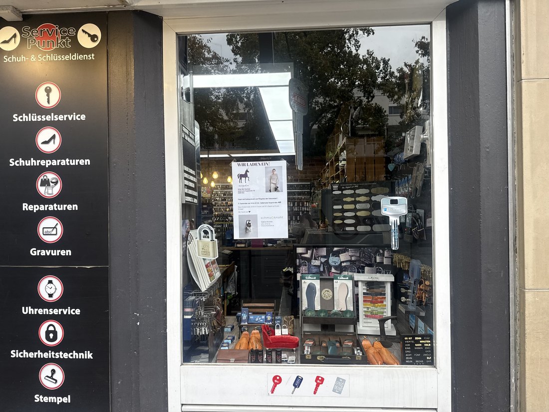 Die Servicetafel am Schaufenster mit Schlüsselservice, Schuhreparaturen, Reparaturen, Gravuren, Uhrenservice, Sicherheitstechnik und Stempel.